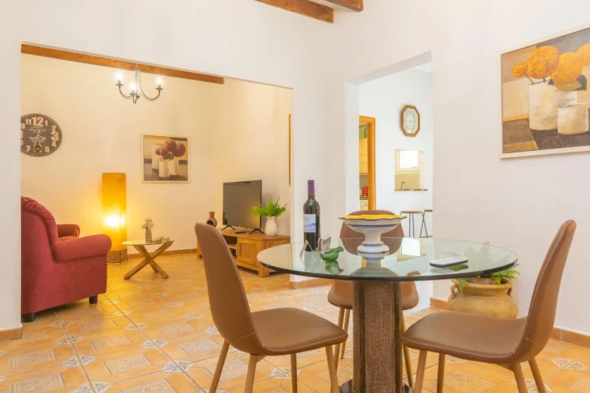 A dining area with a round glass table and seating, opening into a living room.