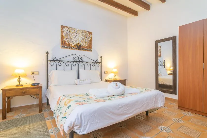 A bedroom with a double bed, bedside tables, and a wardrobe.
