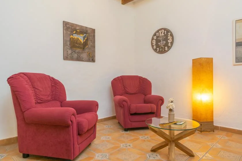 A living room with red seating, a glass coffee table, and a glowing floor lamp.