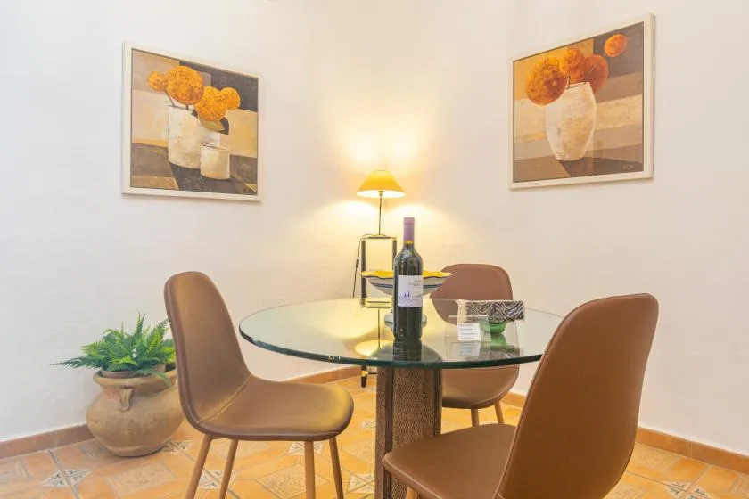 A dining area with a glass table, seating, and framed floral artwork.