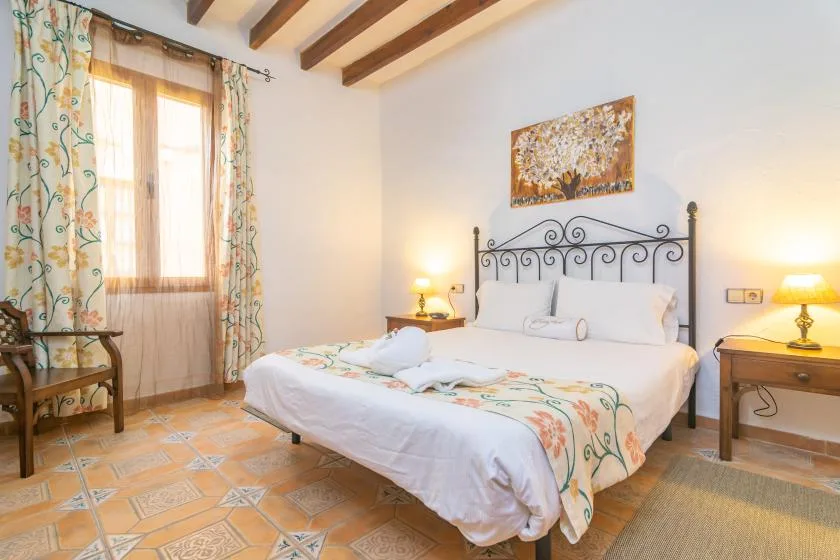 A bedroom with a double bed, bedside tables, and a window with floral curtains.