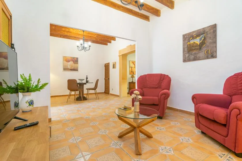A living room with red seating, a glass coffee table, and patterned tile flooring.