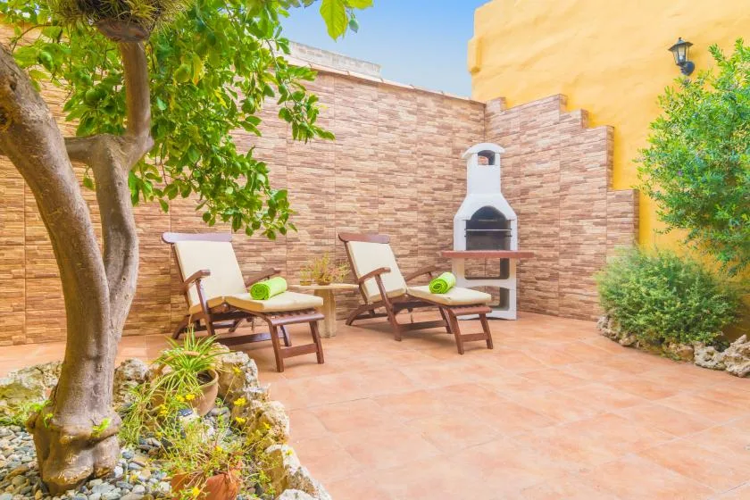 An outdoor patio with reclining seating and a built-in barbecue.