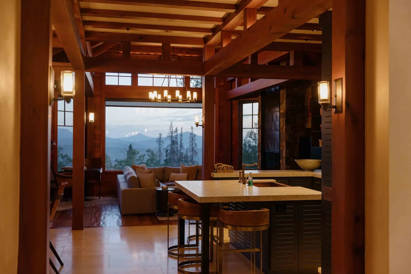 A timber-framed dining area opens onto a living space with mountain views.