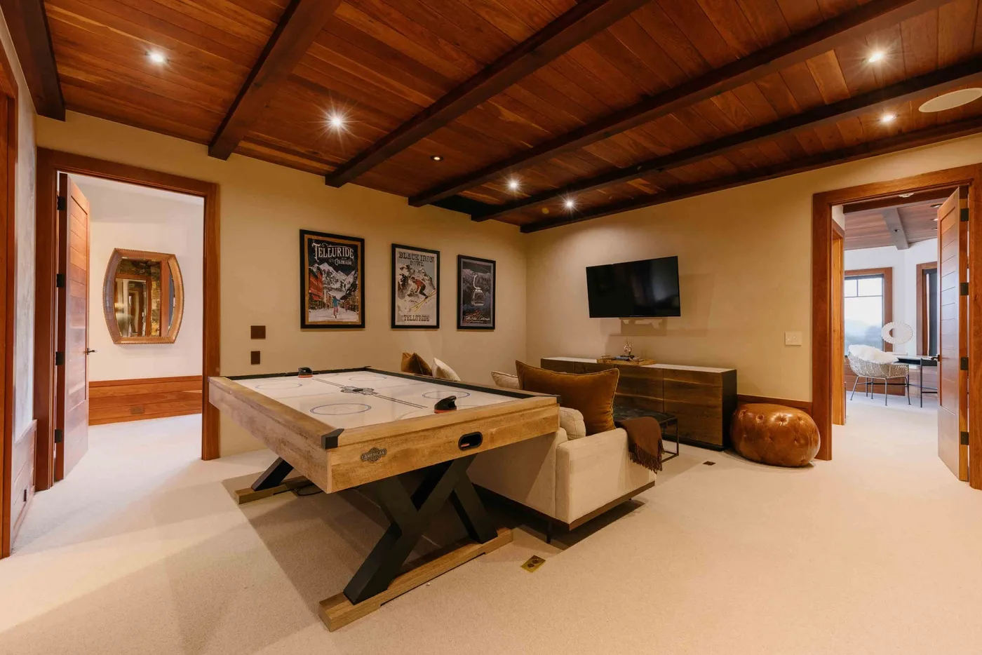 A game room with a pool table, seating, and a wall-mounted television.