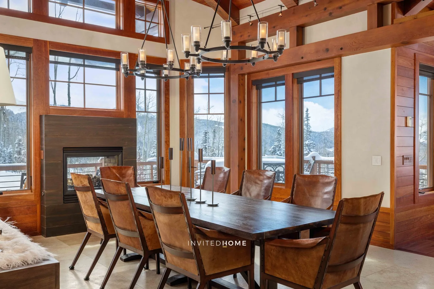 A dining area with a long table and chairs beside a large window.