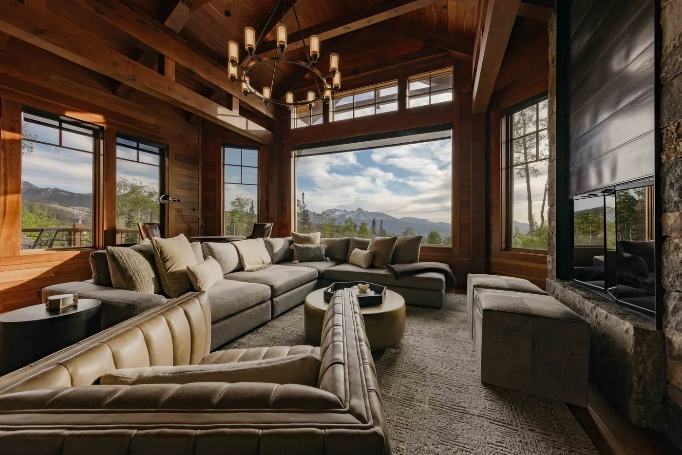 A spacious living room with sectional seating and large windows overlooking a mountain view.