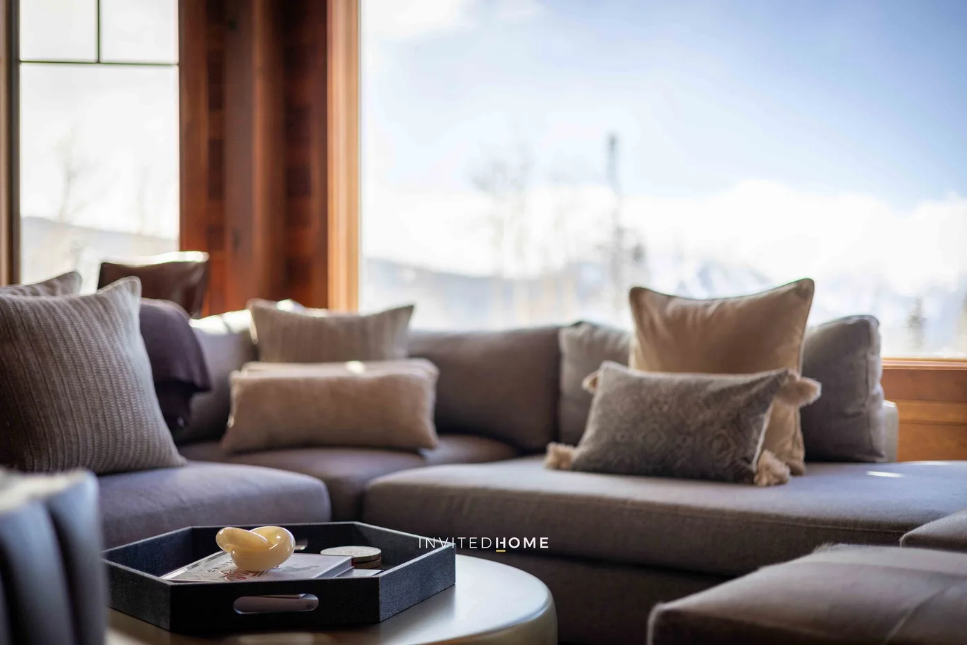 A living room seating area with cushions arranged beside a large window.