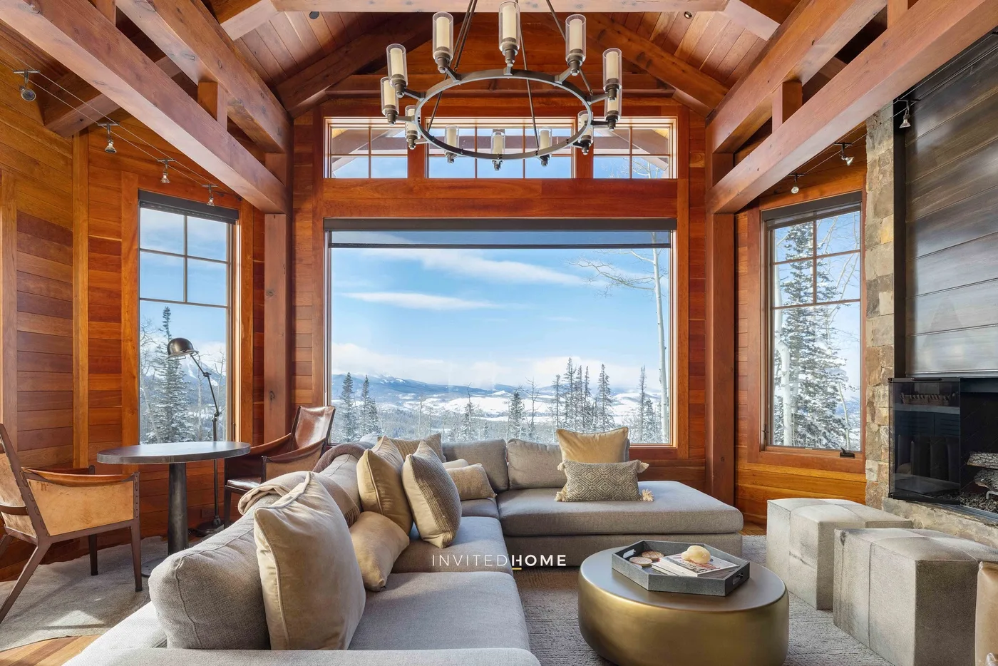 A wood-paneled living room has seating beside large windows overlooking a snowy landscape.