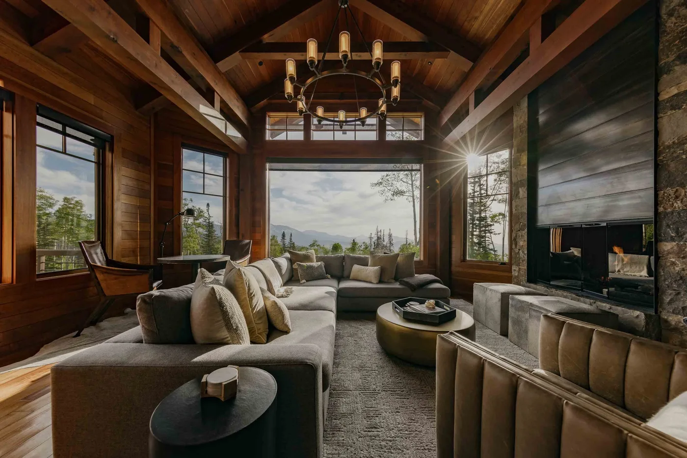 A wood-paneled living room with seating arranged around a fireplace and large windows.