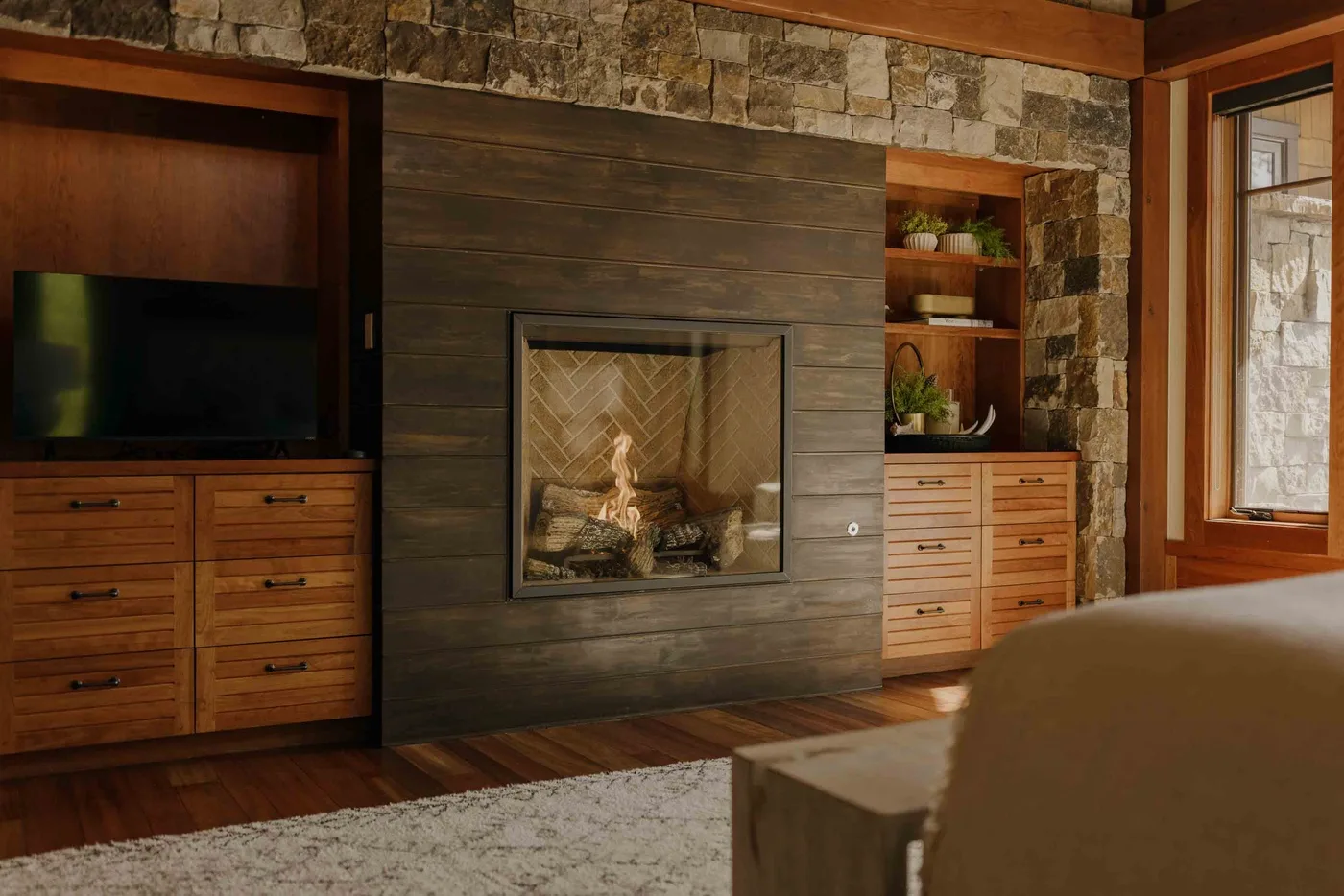 A living room with a fireplace, television, and wooden cabinetry.