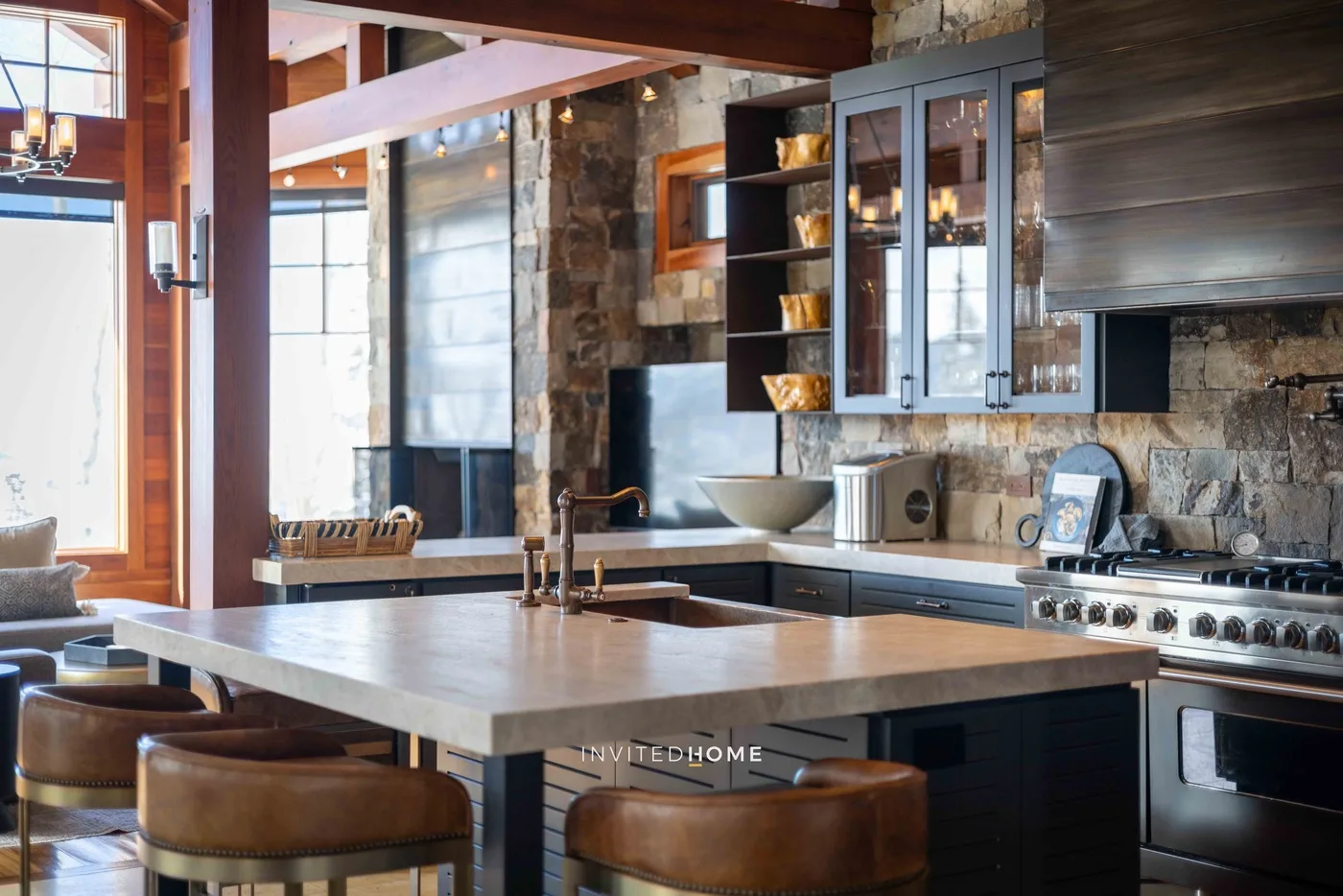 A kitchen with a large island, bar seating, and stone walls.