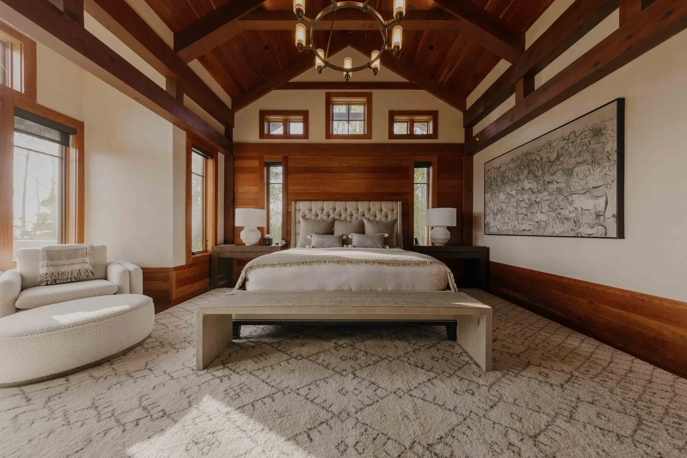 A bedroom with a large bed, a seating area, and exposed wooden ceiling beams.