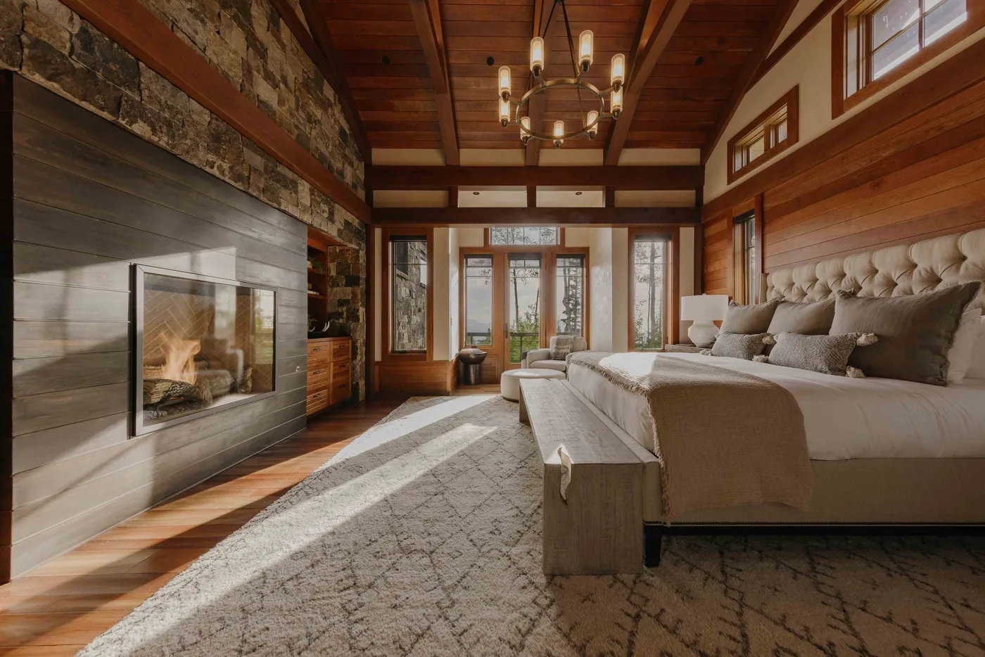 A spacious bedroom features a large bed, a fireplace, and exposed wooden beams.