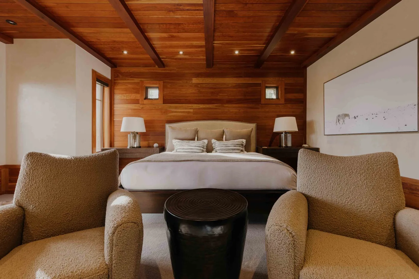A bedroom with a bed, upholstered seating, and a dark round table.