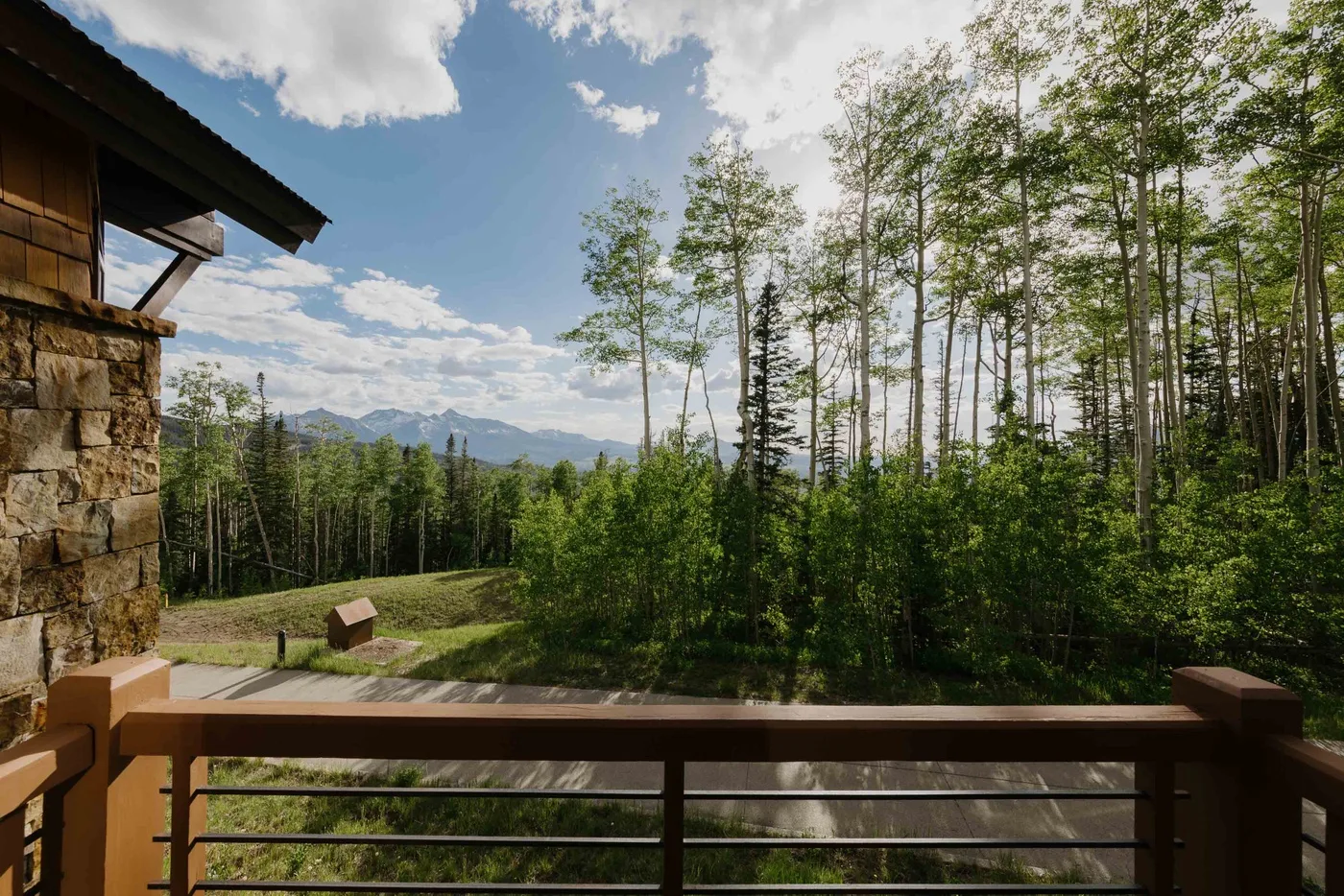 A wooden deck overlooks a forested landscape and distant mountains.