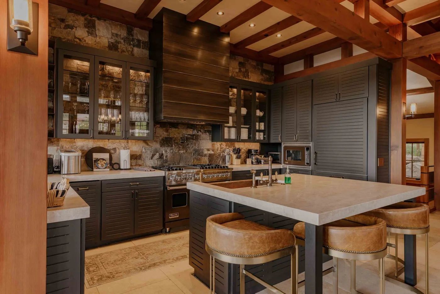 A spacious kitchen with a large island, dark cabinetry, and exposed ceiling beams.