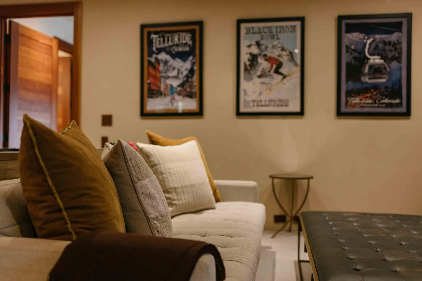 A living room with a cushioned seating area, framed posters, and a small side table.
