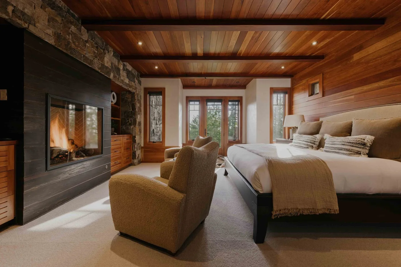 A bedroom with a large bed, upholstered seating, and a built-in fireplace.