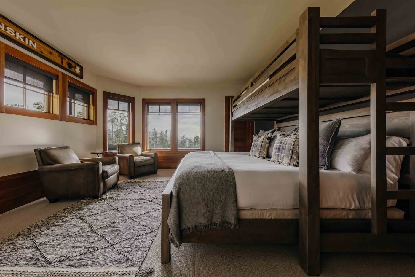 A bedroom with a large bed, bunk beds, and seating beside the windows.