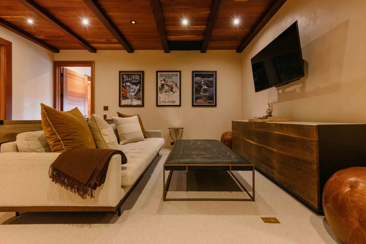 A warm living room with seating, a coffee table, and a wall-mounted television.
