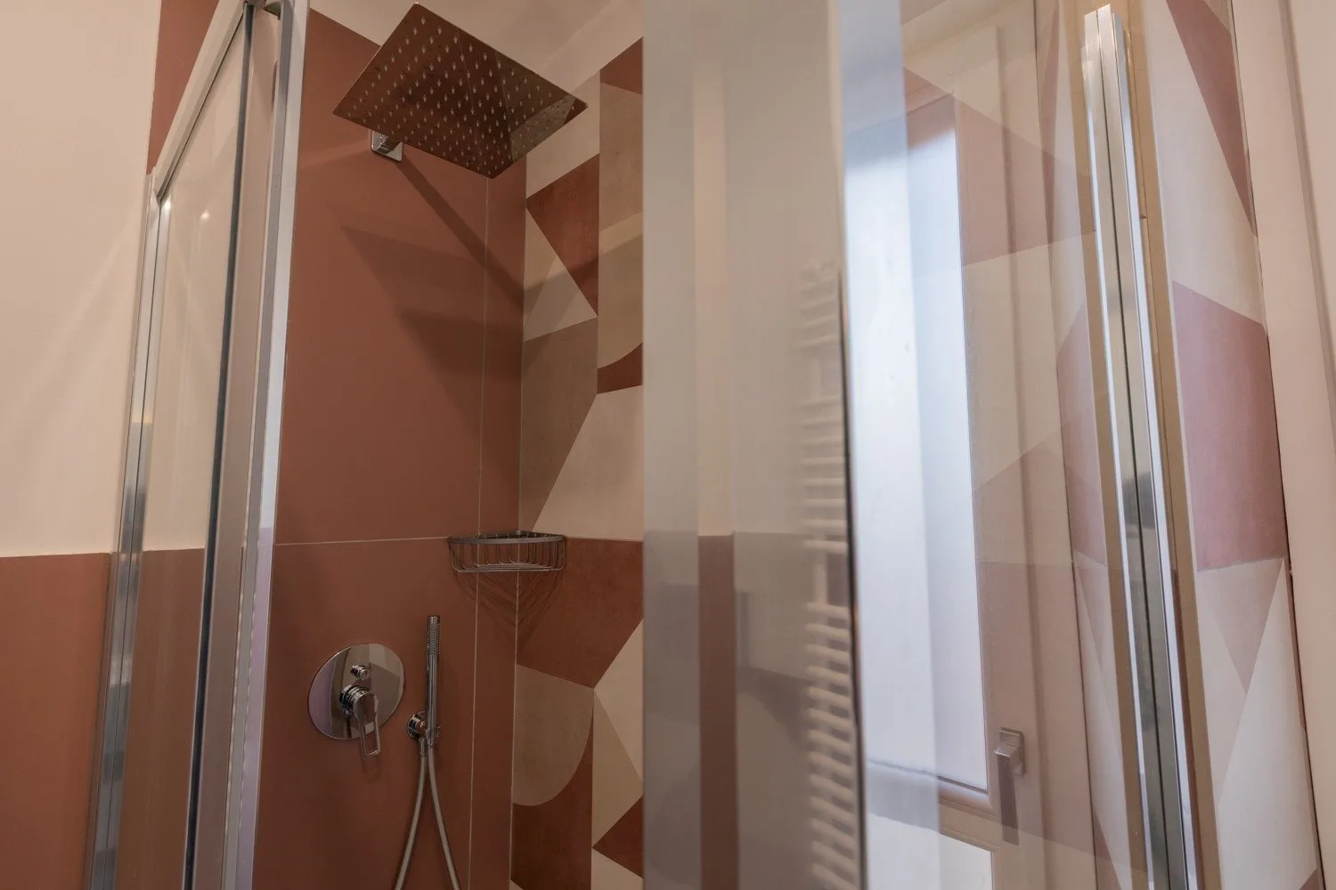 A tiled shower with a large overhead showerhead and glass panels.