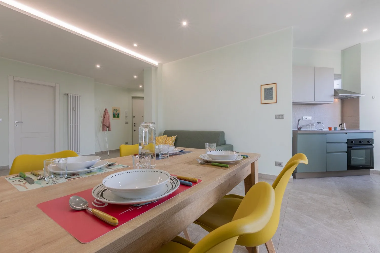 A dining area with a set table and an open kitchen in the background.