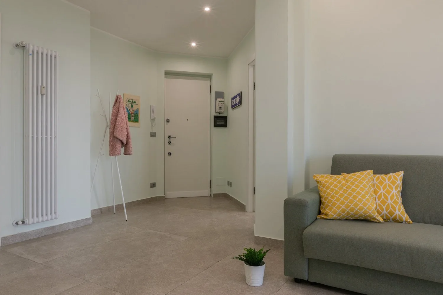 An entry hall with a front door, radiator, and seating area.