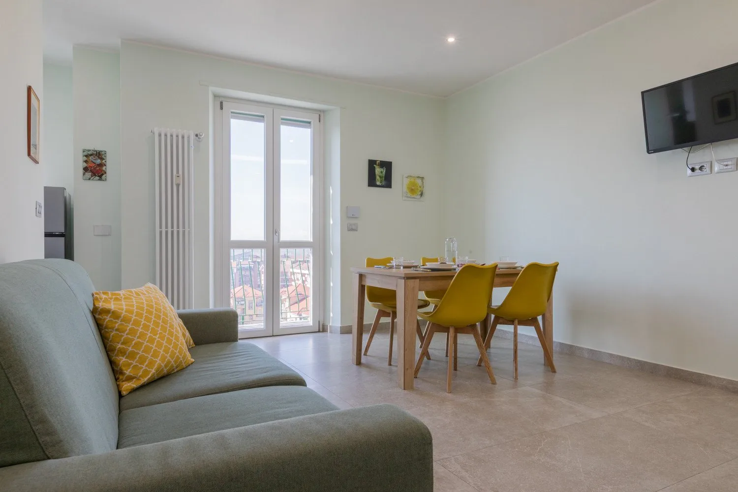 A living and dining area with seating, a dining table, and tall glass doors.