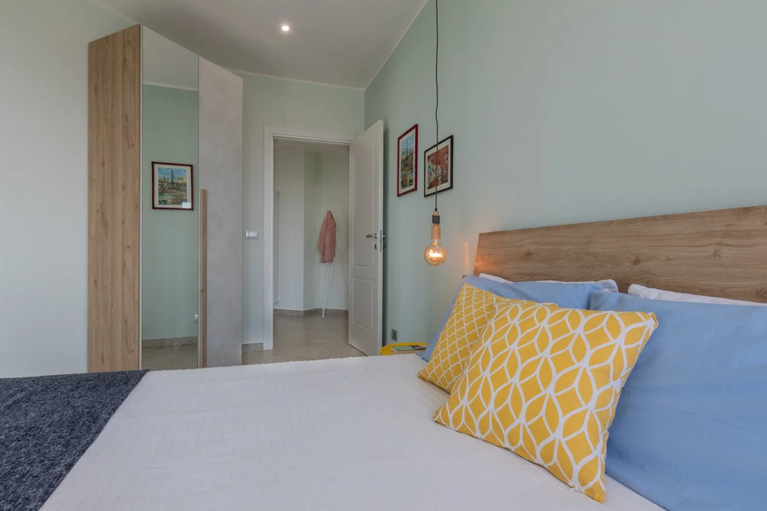 A bedroom with a bed, colorful pillows, and an open doorway.