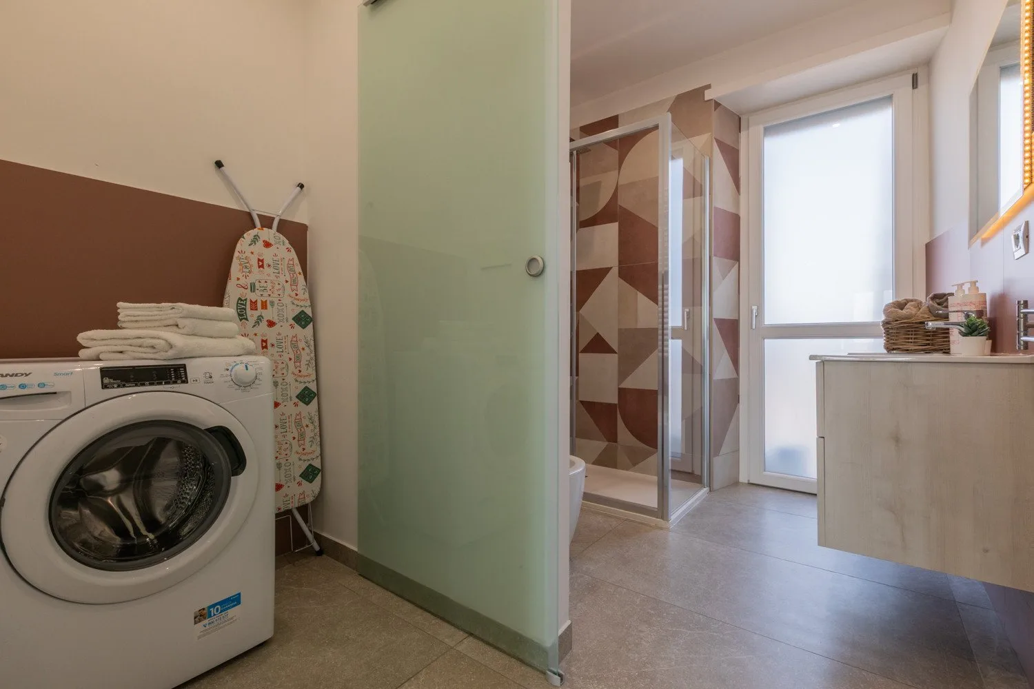A laundry area with a washing machine beside a glass shower.