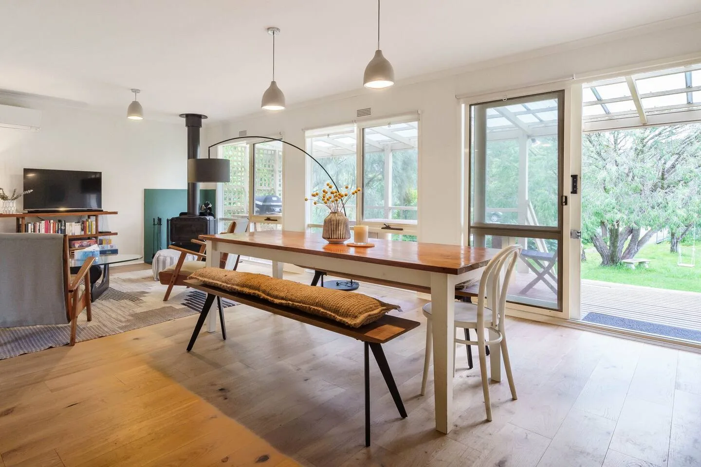 Un comedor luminoso con una mesa larga de madera junto a grandes ventanas.