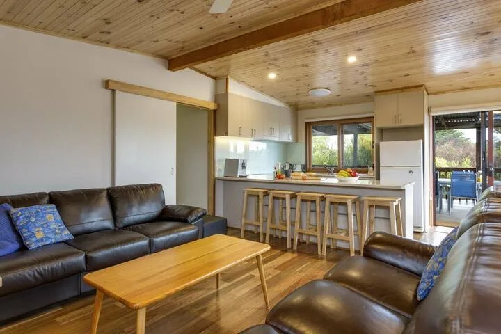 Sala de estar y cocina de concepto abierto con asientos de cuero y barra de desayuno.