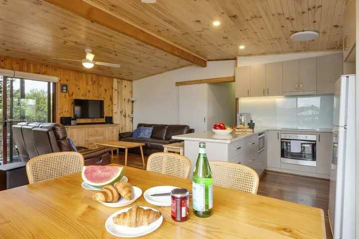 Una sala de estar y cocina de planta abierta con una mesa de comedor en primer plano.