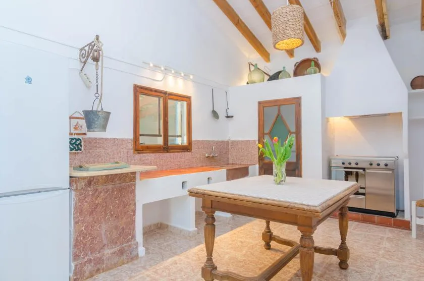 A bright kitchen with a large wooden table and a built-in oven.