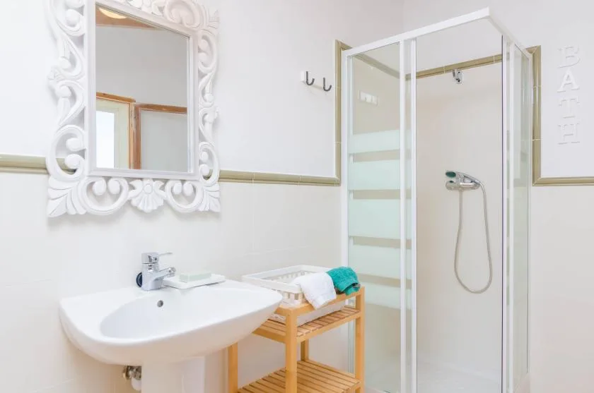 A bright bathroom with a sink, wall mirror, and glass shower.