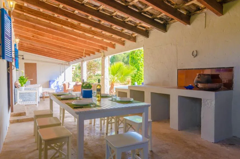 A covered outdoor dining area with a long table and built-in counter.