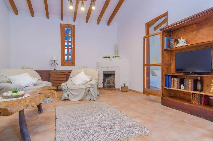 A bright living room with seating, a fireplace, and a wooden entertainment unit.