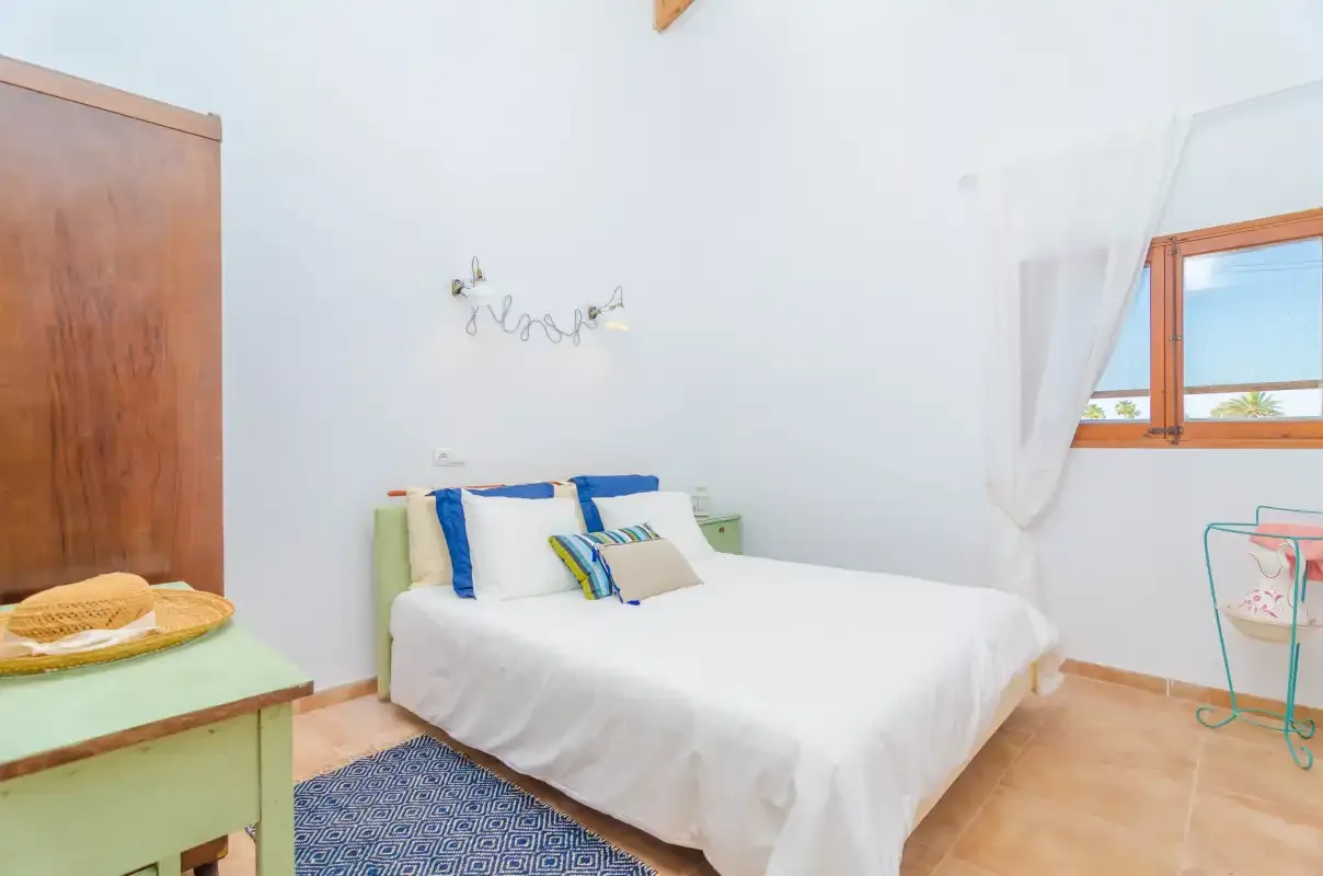A bedroom with a double bed, colorful pillows, and a small bedside table.
