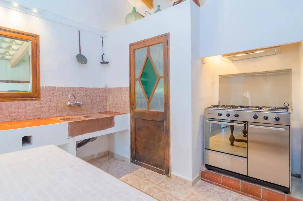 A kitchen with a sink, a stove, and a wooden door.