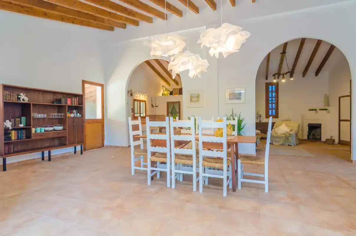 A spacious dining area with a wooden table, chairs, and exposed ceiling beams.