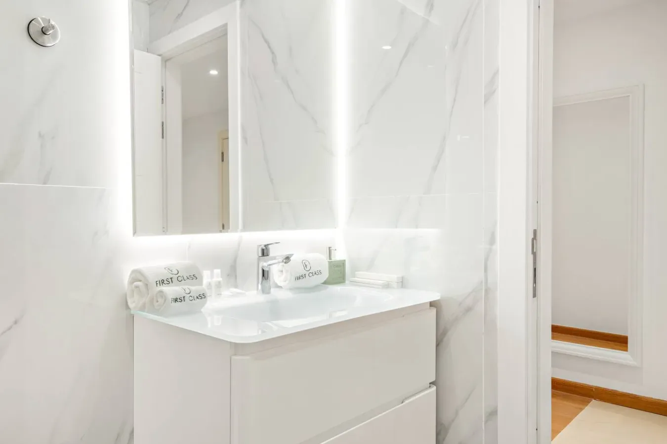 Un tocador de baño luminoso con un espejo amplio y paredes claras con vetas.