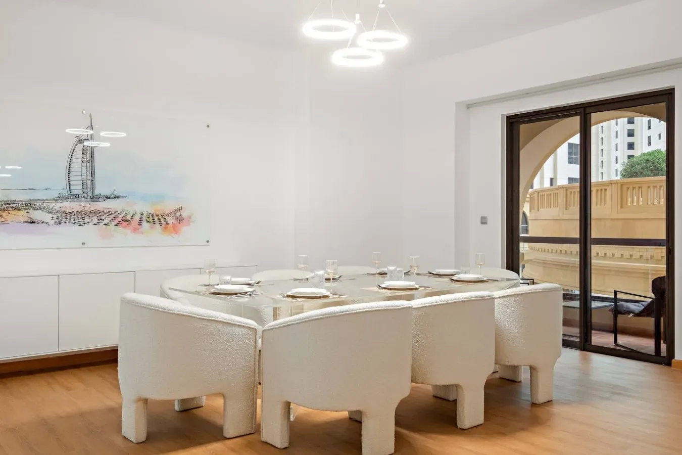 Un comedor luminoso con asientos blancos alrededor de una mesa.