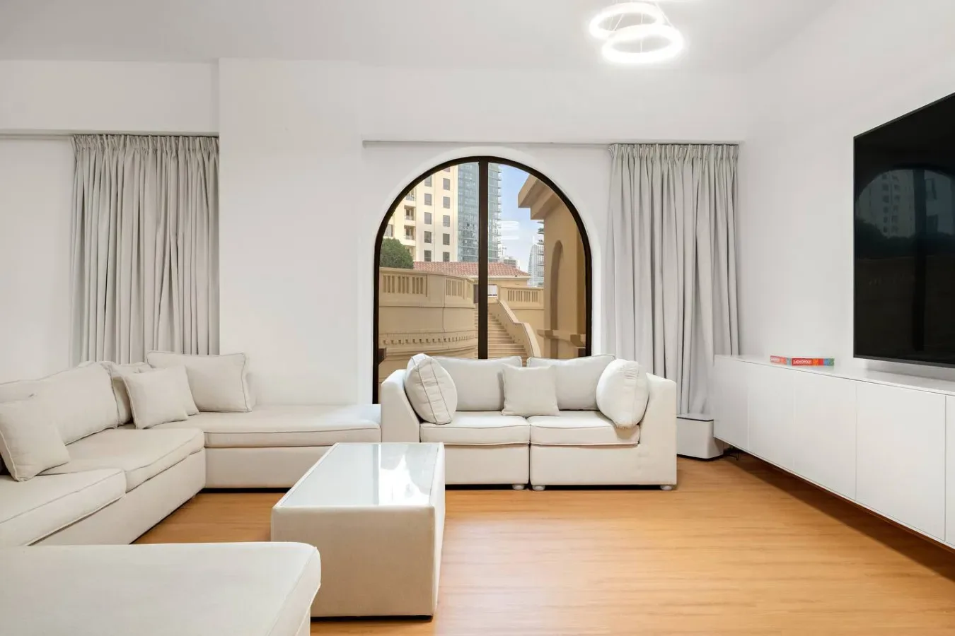 Una sala de estar luminosa con asientos blancos alrededor de una mesa de centro baja.