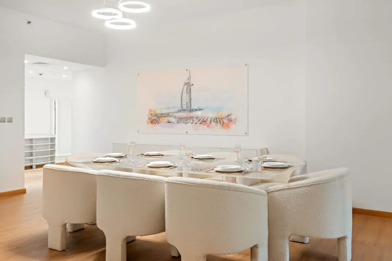 Un comedor luminoso con una mesa larga preparada bajo una obra de arte colorida.