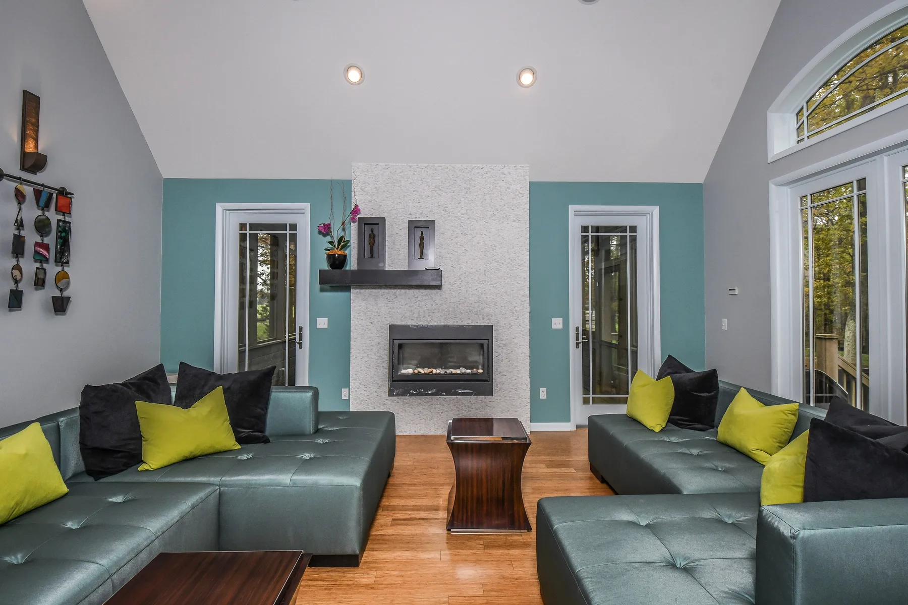 A living room with teal seating arranged around a fireplace.