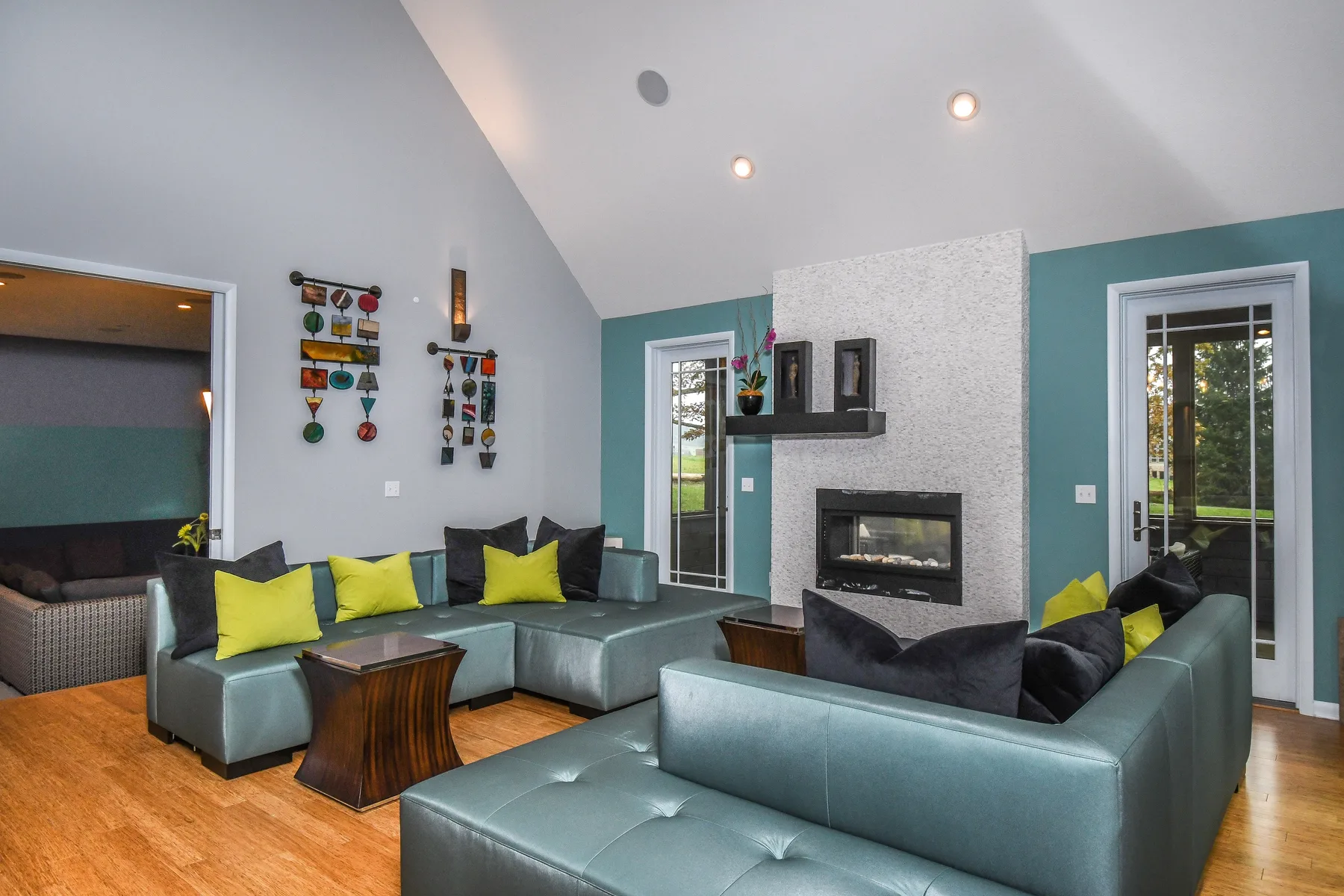 A living room with teal sectional seating arranged around a fireplace.