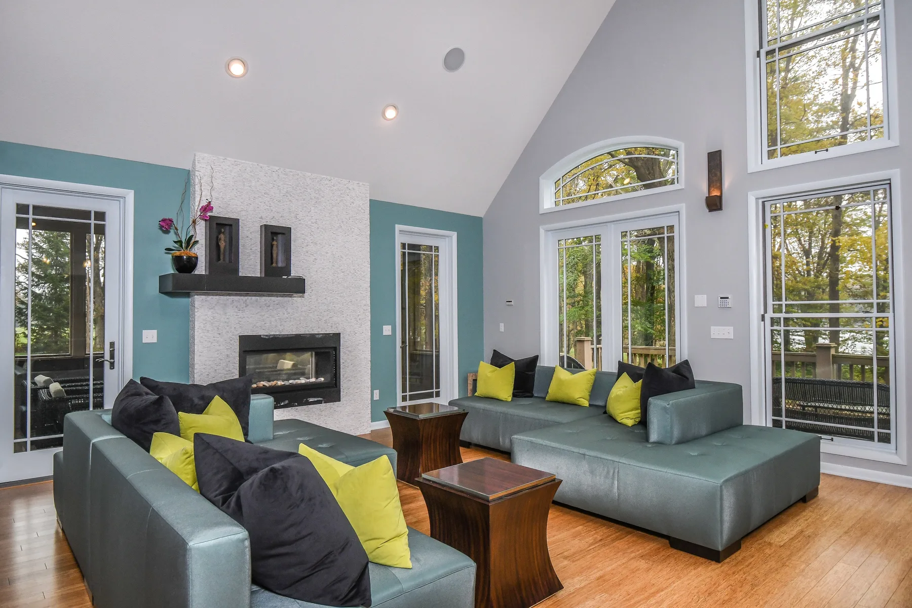 A bright living room with gray seating, yellow cushions, and a fireplace.