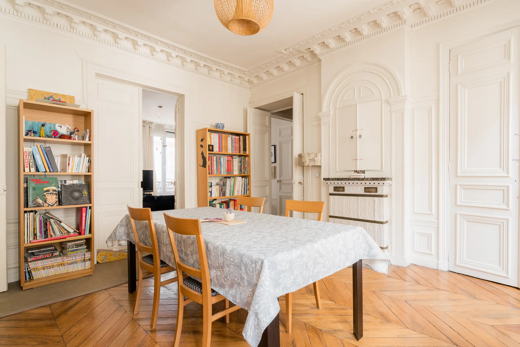A dining room with a long table and chairs, bookshelves, and ornate wall paneling.