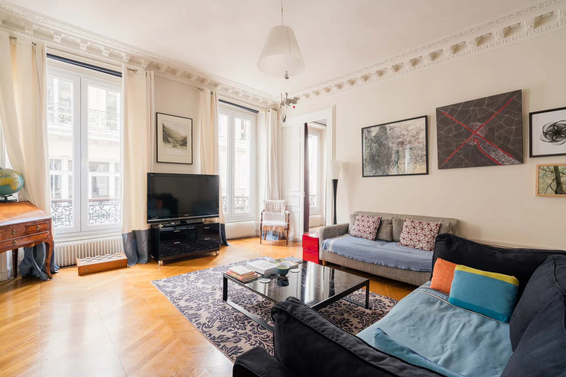 A bright living room with large windows, sofas, and a coffee table.